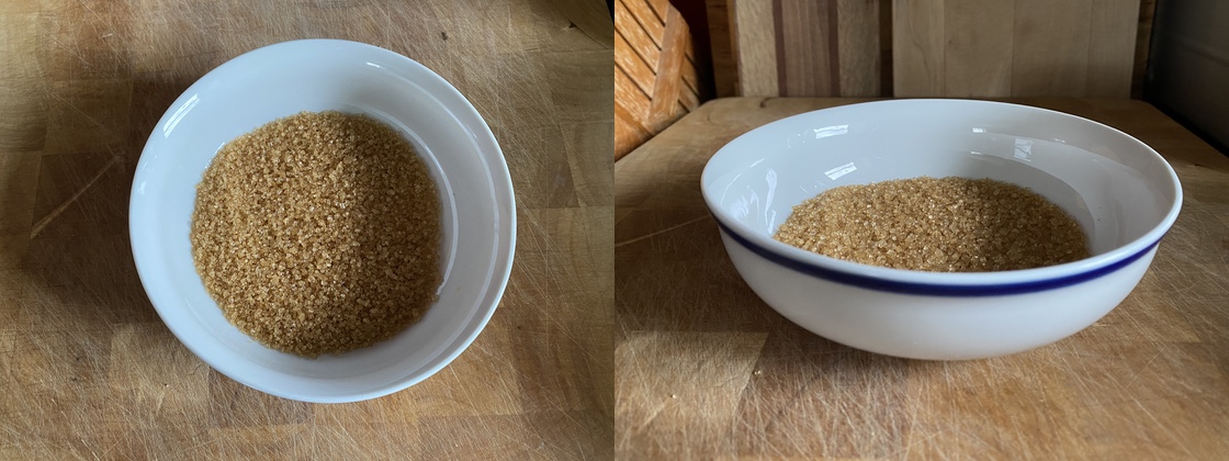 Coarse, dark, granulated sugar placed in a low rimmed ceramic bowl.